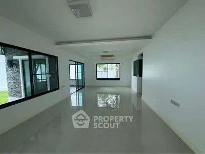 Spacious modern living room with large windows and glossy tiled floors