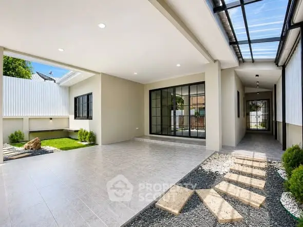 Modern open-plan home with sleek design and spacious outdoor area, featuring large windows and a stylish walkway.