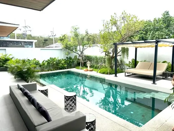 Luxurious outdoor pool area with lush greenery and stylish seating, perfect for relaxation and entertainment.