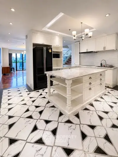 Luxurious kitchen with marble island and unique geometric flooring in modern open layout home.