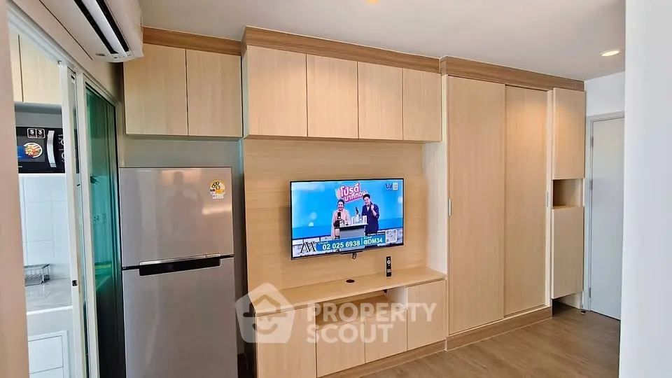 Modern apartment interior with built-in wooden cabinets and mounted TV