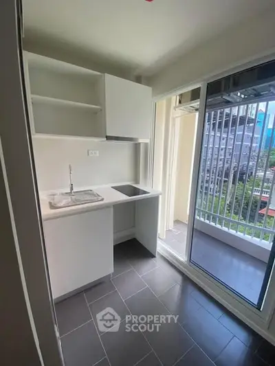 Modern compact kitchen with balcony view in urban apartment