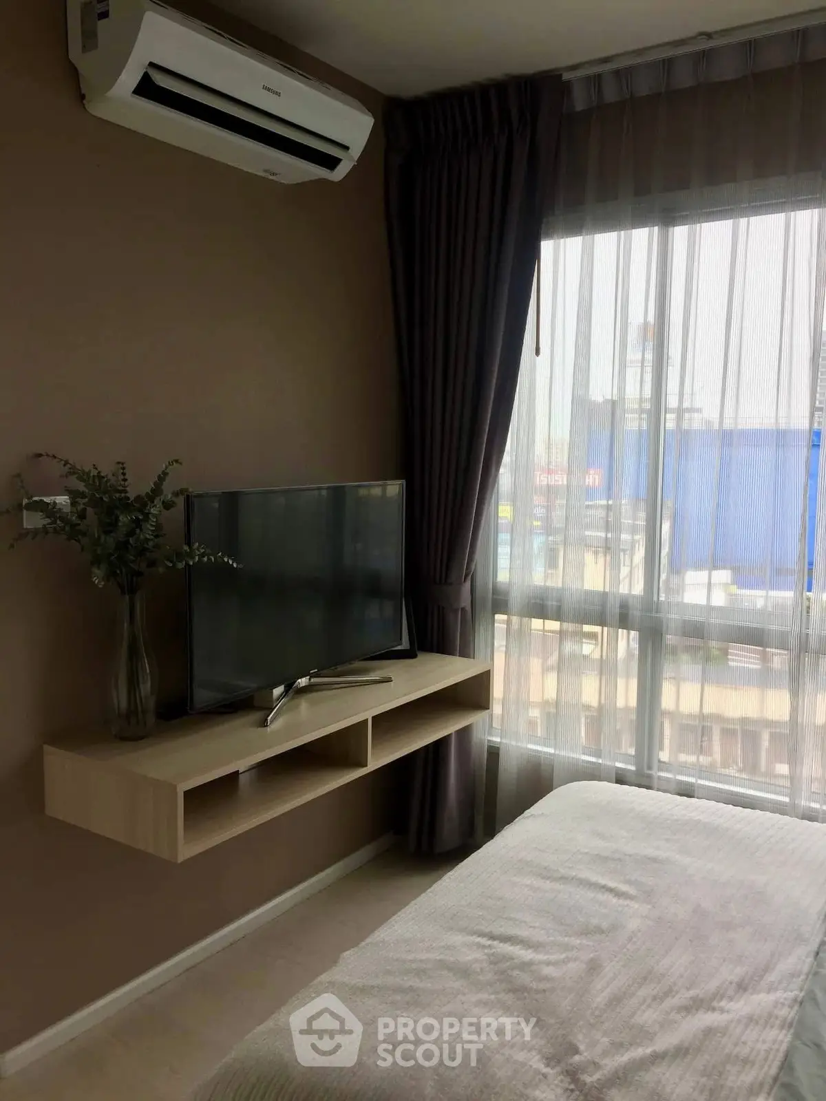 Cozy bedroom with modern TV setup and large window view