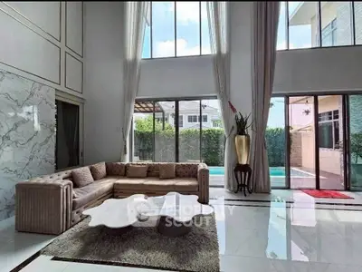 Luxurious living room with high ceilings and pool view, featuring elegant decor and modern furniture.
