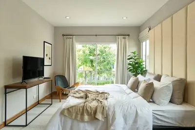 Spacious bedroom with modern decor and large window overlooking greenery.