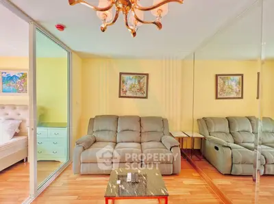 Luxurious living room with elegant chandelier and mirrored wall, featuring plush sofa and stylish decor.