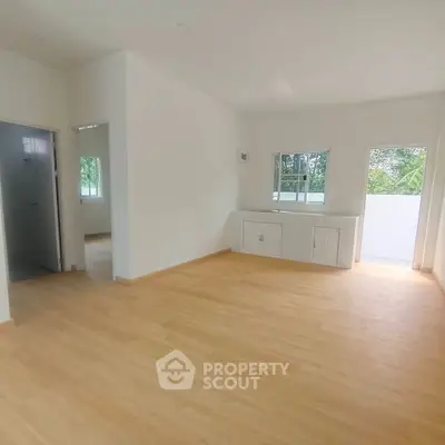 Spacious empty room with wooden flooring and natural light, ideal for customization.