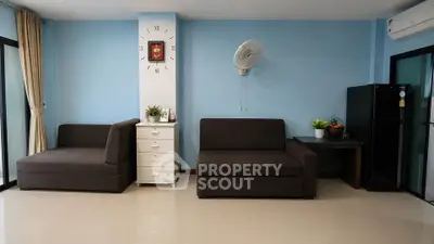 Spacious living room with modern furniture and wall clock, perfect for relaxation and entertaining.