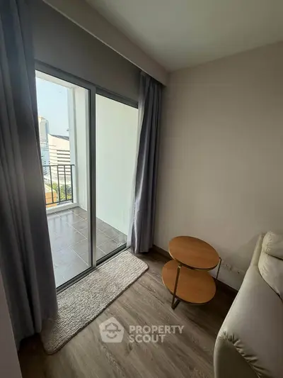 Cozy living room with balcony access and modern furniture in urban apartment.