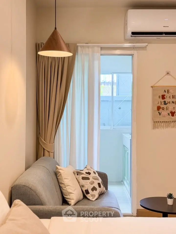 Cozy living room with modern decor and air conditioning, featuring a comfortable sofa and stylish lighting.