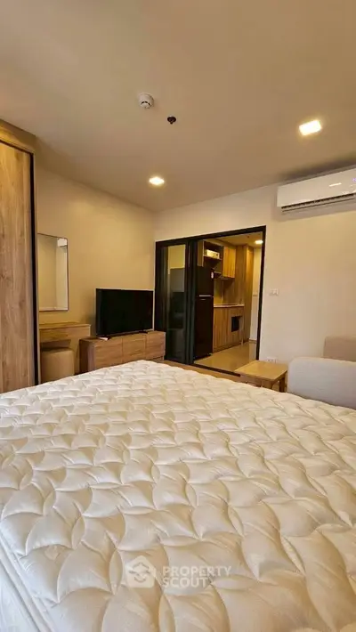 Modern bedroom with cozy bed, TV, and air conditioning in stylish apartment.