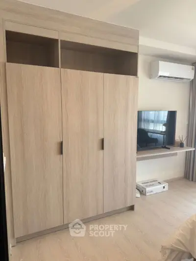 Modern bedroom with sleek wardrobe and wall-mounted TV in stylish apartment.