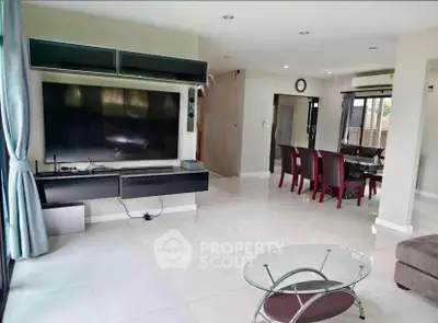 Spacious modern living room with large TV and elegant dining area, perfect for entertaining.