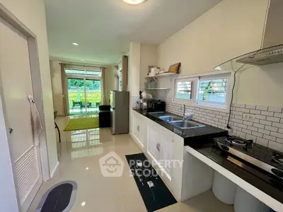 Modern kitchen with open layout and garden view, featuring sleek appliances and stylish decor.