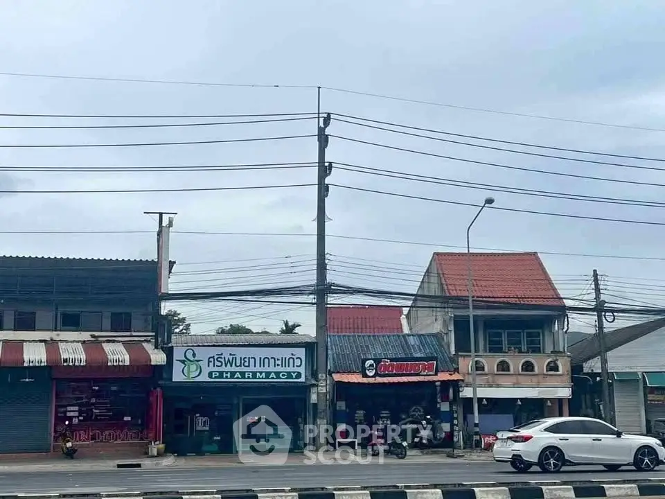 Street view of commercial buildings with pharmacy and shops, showcasing urban retail opportunities.