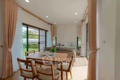 Spacious living room with elegant dining area and large windows offering garden views.