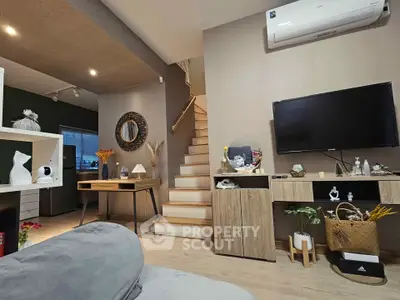 Modern living room with stylish decor, wooden staircase, and wall-mounted TV in a cozy home setting.