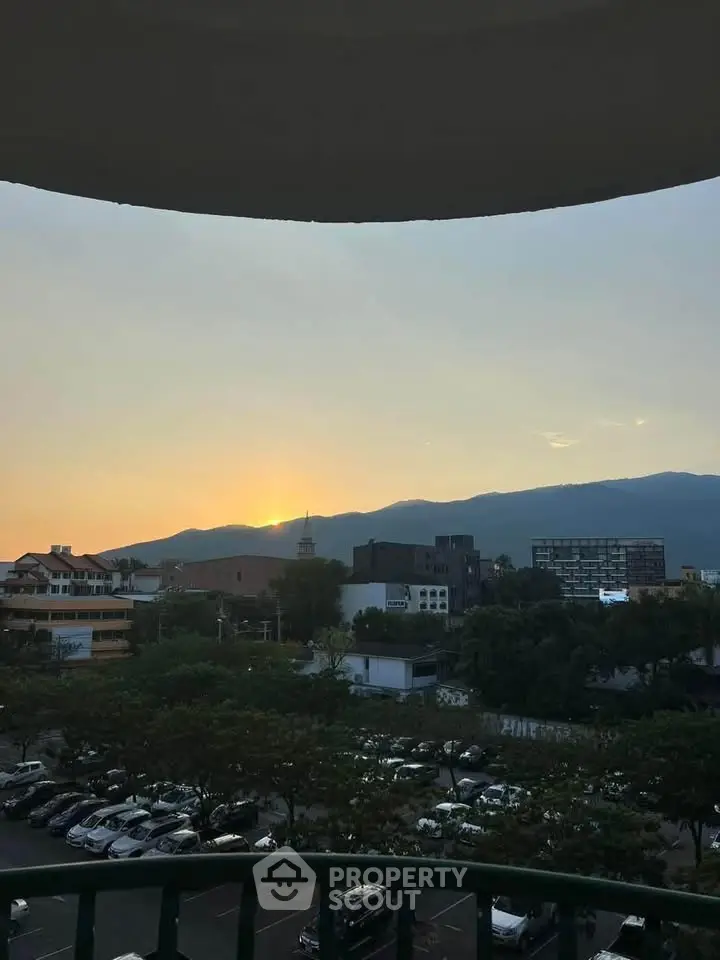 Stunning sunset view from a balcony overlooking cityscape and mountains.