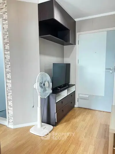 Modern living room with sleek TV stand and fan, featuring wooden flooring and stylish wall decor.