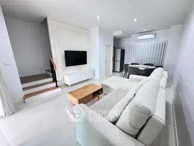 Modern living room with sleek white furniture and open dining area
