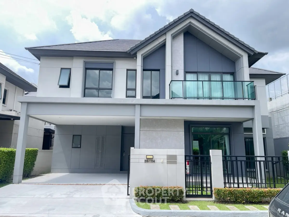 Modern two-story house with sleek design and glass balcony in suburban neighborhood.