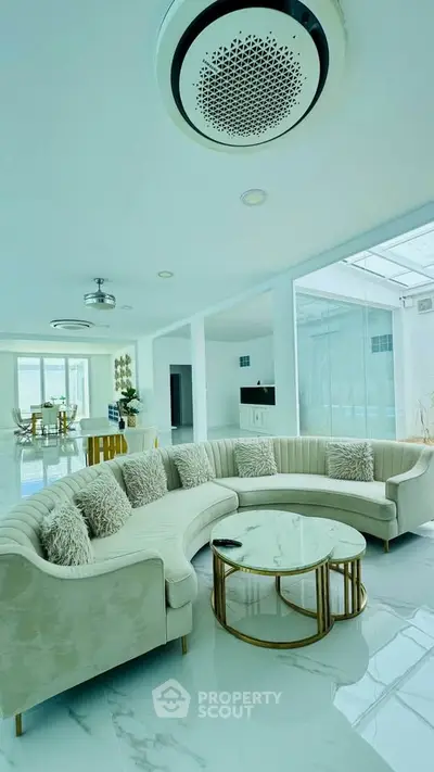 Luxurious living room with elegant curved sofa and marble coffee table in modern open-plan design.