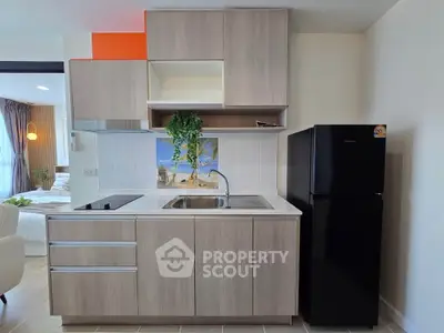 Modern kitchen with sleek cabinetry and black fridge in stylish apartment.