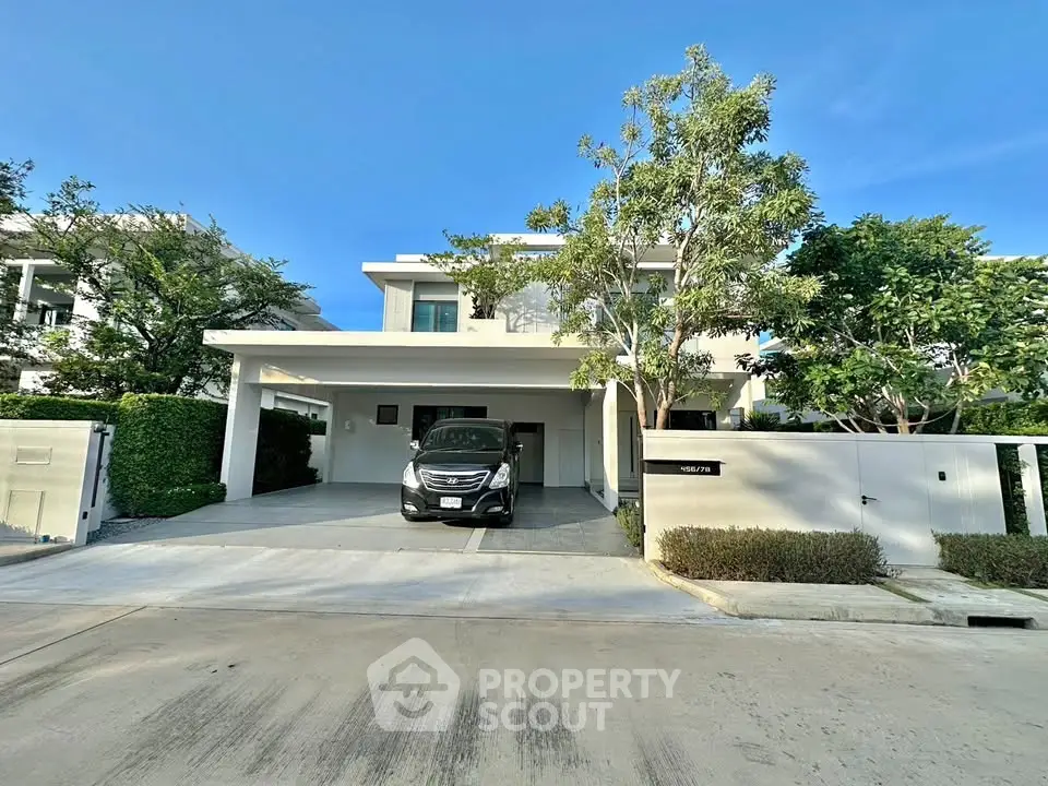 Modern two-story house with driveway and lush greenery in a serene neighborhood.