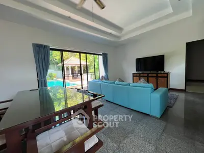 Spacious living room with pool view, modern furniture, and large windows in a luxury home.