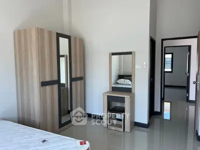 Modern bedroom with sleek wardrobe and vanity set, showcasing minimalist design and ample natural light.