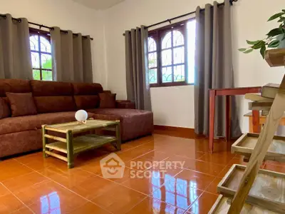 Charming living room with cozy brown sofa and natural light through arched windows.