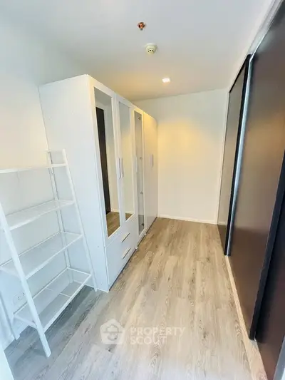 Spacious walk-in closet with modern white wardrobes and wooden flooring