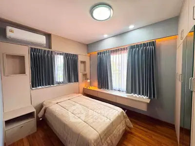 Cozy bedroom with modern design, featuring wooden flooring and ample natural light through large windows.