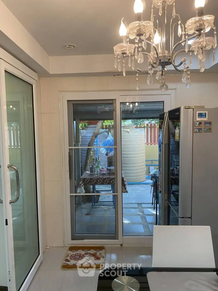 Chic kitchen with chandelier and sliding doors leading to a cozy outdoor patio.