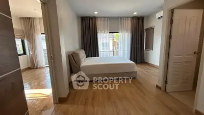 Spacious bedroom with wooden flooring and large windows in modern home