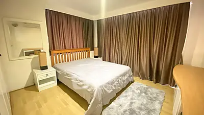 Spacious bedroom with cozy lighting and elegant curtains in modern apartment.