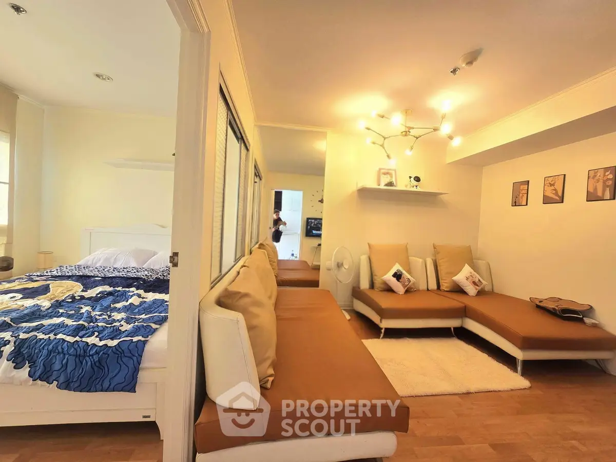 Spacious living room with modern decor and cozy bedroom in open layout apartment.