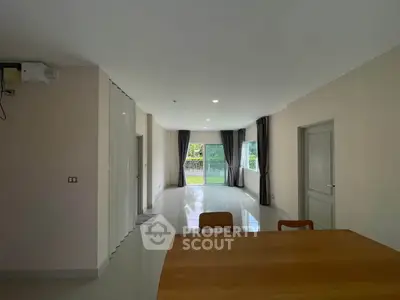 Spacious modern living room with large windows and garden view, perfect for family gatherings.