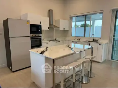 Modern kitchen with sleek appliances and marble island in a bright open layout.