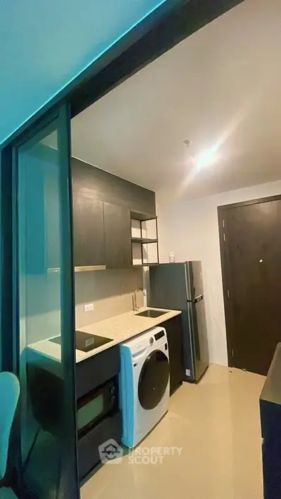Modern compact kitchen with sleek appliances and stylish cabinetry in a contemporary apartment.