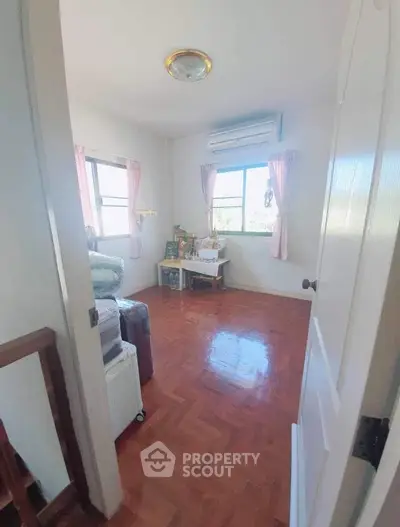 Cozy bedroom with wooden flooring and natural light from large windows.