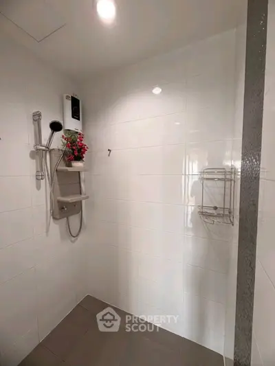 Modern bathroom shower area with sleek white tiles and contemporary fixtures.
