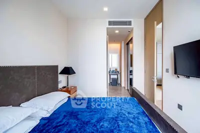 Modern bedroom with blue bedding and wall-mounted TV in a stylish apartment.