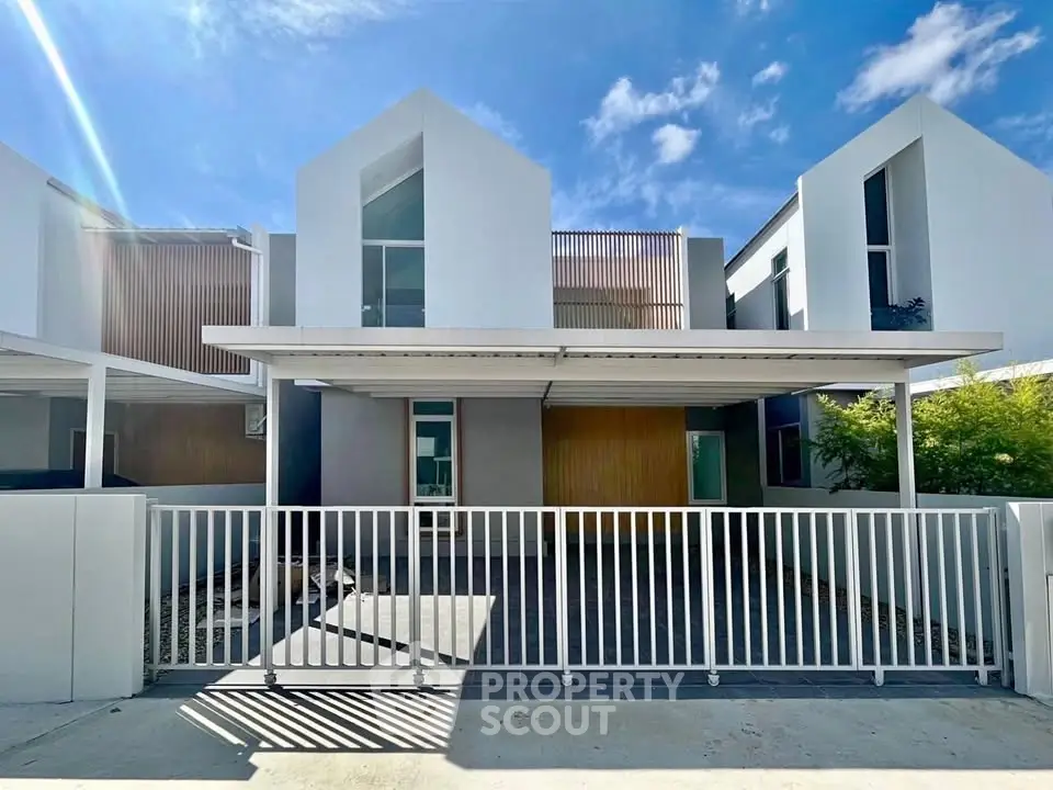 Modern minimalist townhouse with sleek design and spacious driveway under a clear blue sky.
