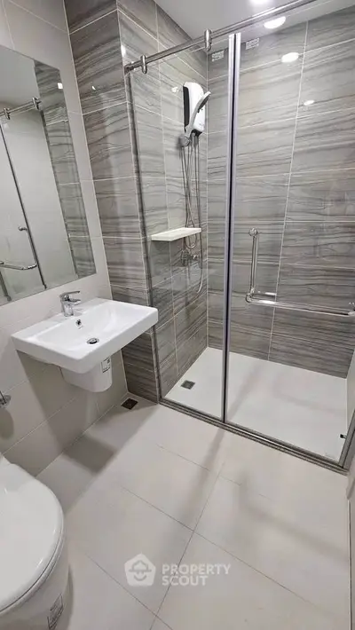 Modern bathroom with sleek shower enclosure and stylish sink in contemporary apartment.