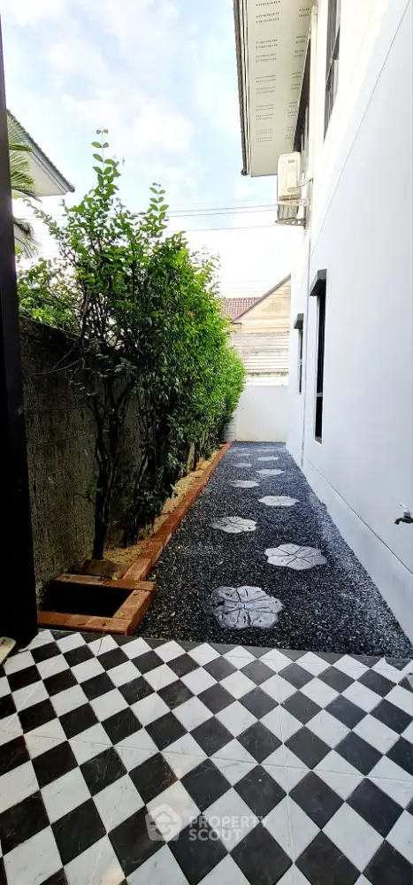 Charming narrow garden path with modern checkered tiles and lush greenery