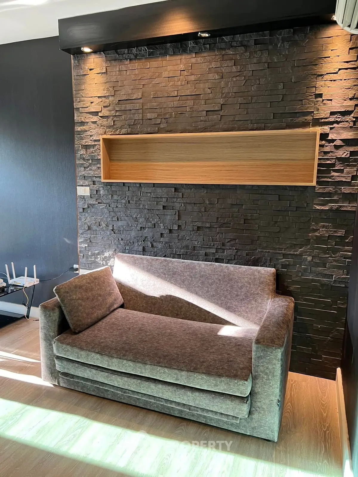 Modern living room with stylish stone accent wall and cozy sofa, perfect for relaxation.