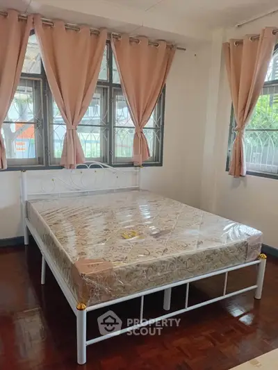 Spacious bedroom with large windows and elegant curtains, featuring a new bed with a comfortable mattress.