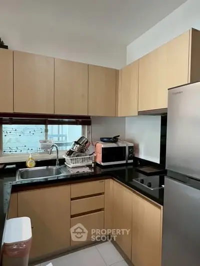 Modern kitchen with sleek cabinetry and stainless steel appliances in a cozy apartment.