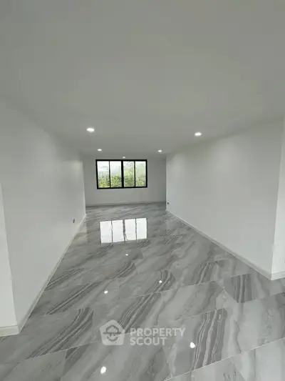 Spacious modern living room with glossy marble flooring and large windows offering natural light.